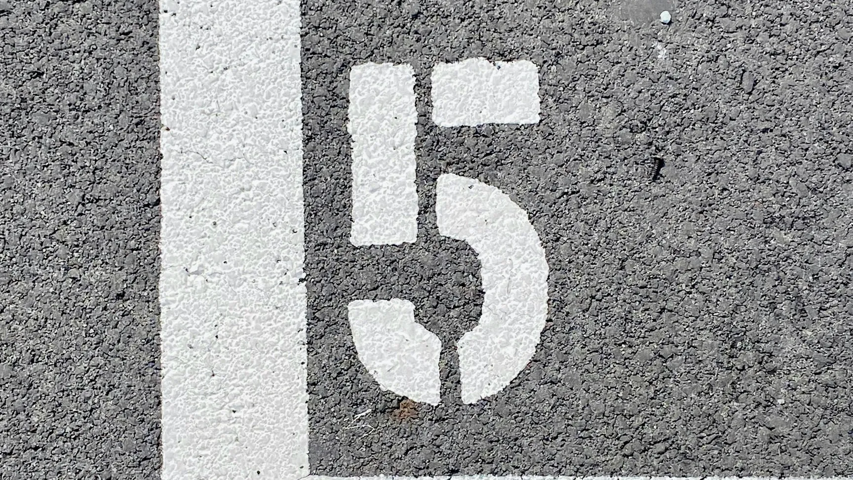 Talrige på en grå asfalt overflade med hvid nummer 5 inden for en hvid kantlinje.