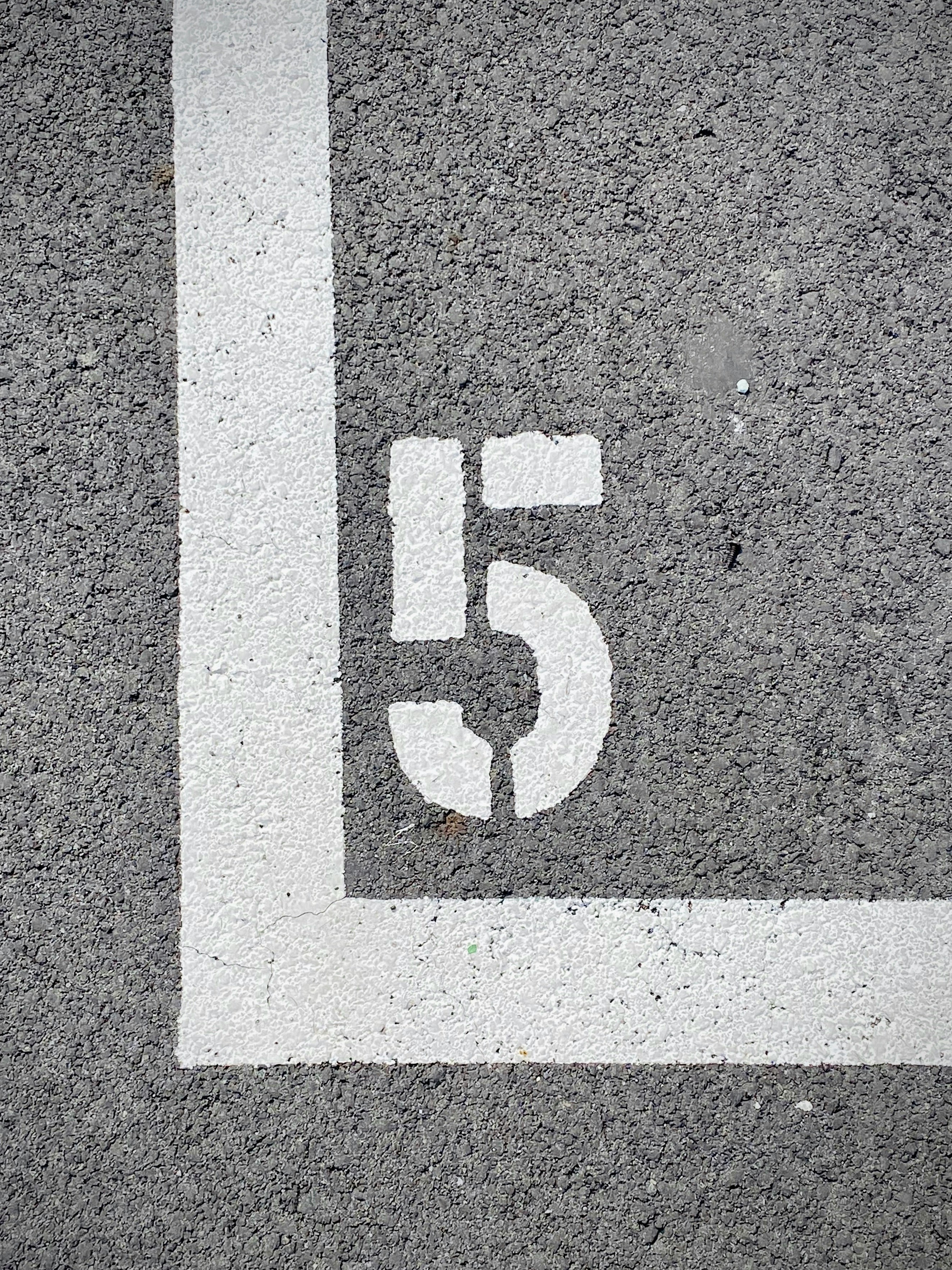 Talrige på en grå asfalt overflade med hvid nummer 5 inden for en hvid kantlinje.
