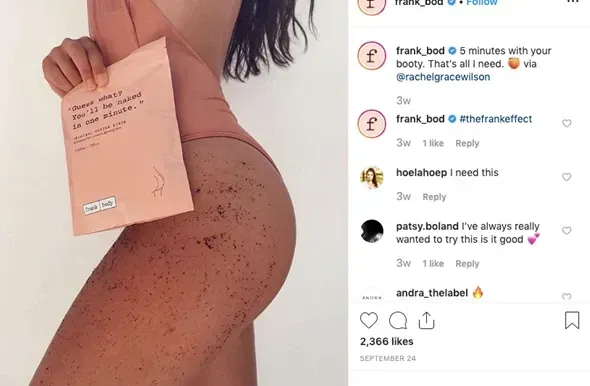 En person står med ryggen til og holder en skønhedsproduktpakke fra frank_body, mens de viser huden med exfolierende scrubs.