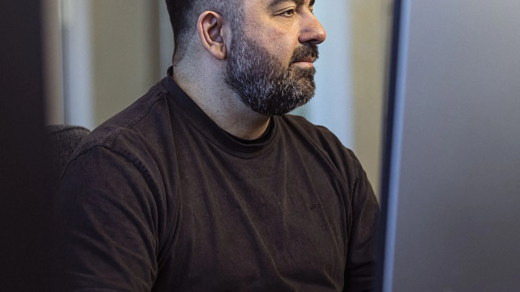 Mand med skæg arbejder koncentreret ved en computer i et moderne kontormiljø.