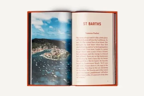 Åben bog med en flyvning over St. Barth's, der viser en kystlinje med både og en strand, ved siden af tekst om øens oplevelser.