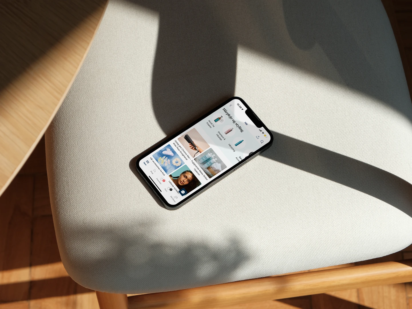 A smartphone displaying a shopping app with product images and a focus on beauty items, resting on a light-colored chair, illuminated by natural sunlight.