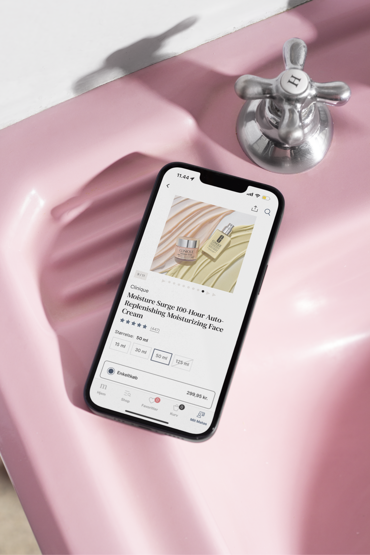 Smartphone viser produktinformation for Clinique Moisture Surge 100-Hour Auto-Replenishing Moisturizing Face Cream ved en pink vask med en metalvandhane.