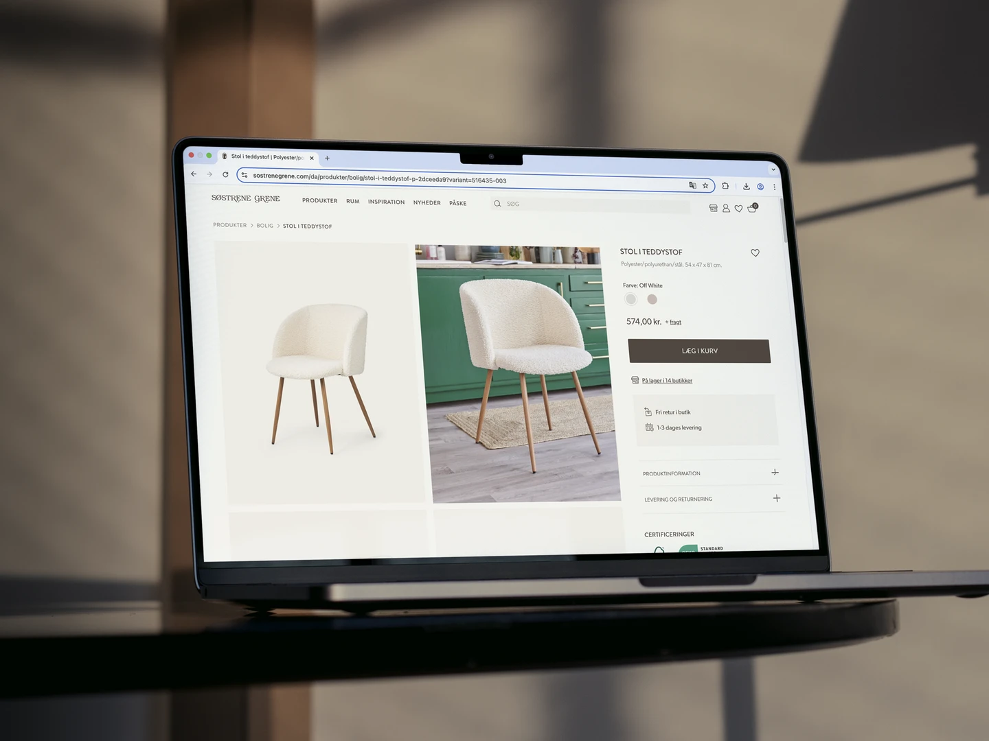 En moderne stol i teddystof med let buede arme og tre ben af træ, præsenteret på en skærm med produktinformation og detaljer.