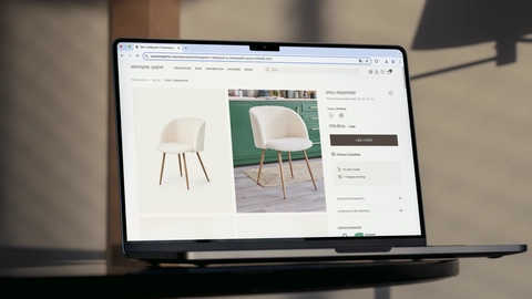 A laptop displaying a product page featuring a stylish off-white teddy fabric chair with wooden legs, alongside product details and a green kitchen backdrop.