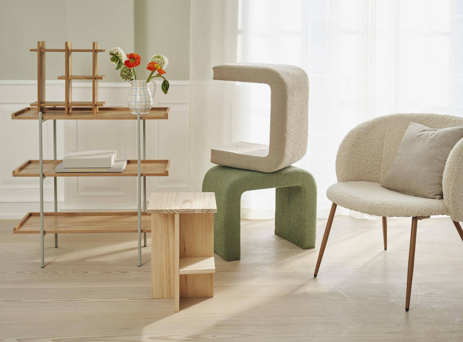 En moderne stue med en træhylde, en blød, geometrisk stol i beige og grøn farve, en lille træbord med to rum og en vase med farverige blomster.