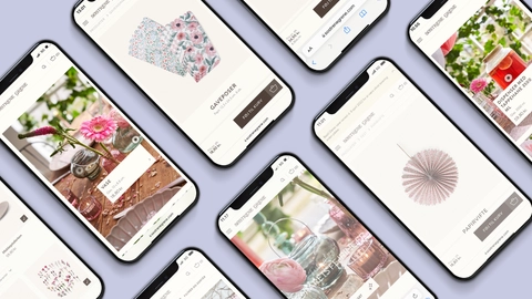 Billede af flere smartphones, der viser forskellige produktsider fra Søstrene Grene, herunder gaveposer, vaser og dekorationselementer med en blød lilafarvet baggrund.
