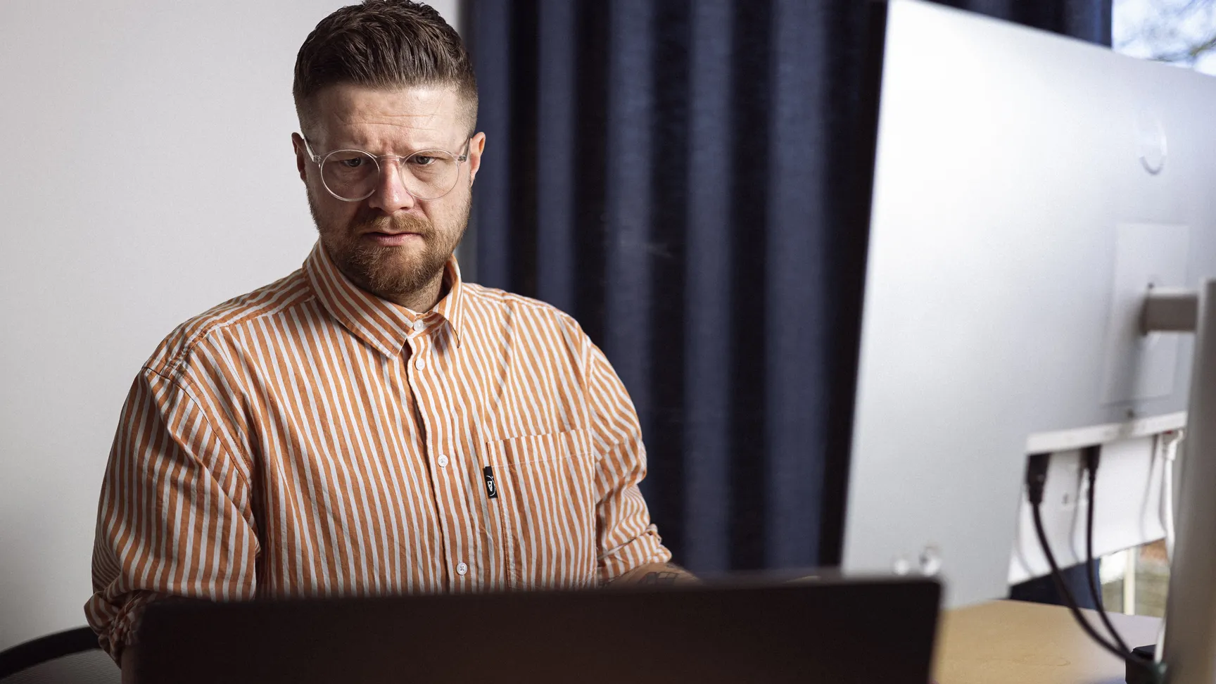 Mand sidder i en kontor setting foran sin computer, han ser konsentreret ud