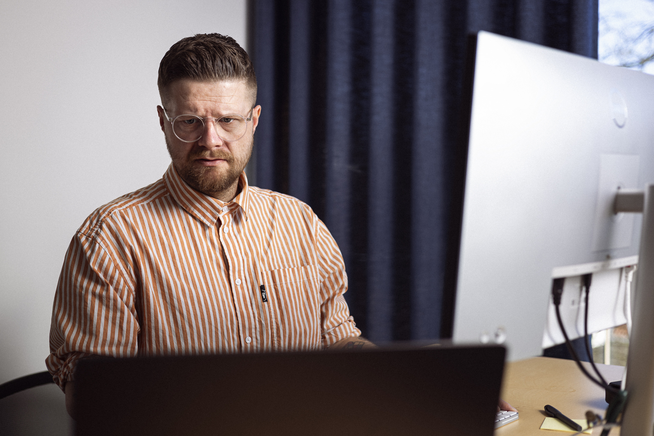 Mand sidder i en kontor setting foran sin computer, han ser konsentreret ud