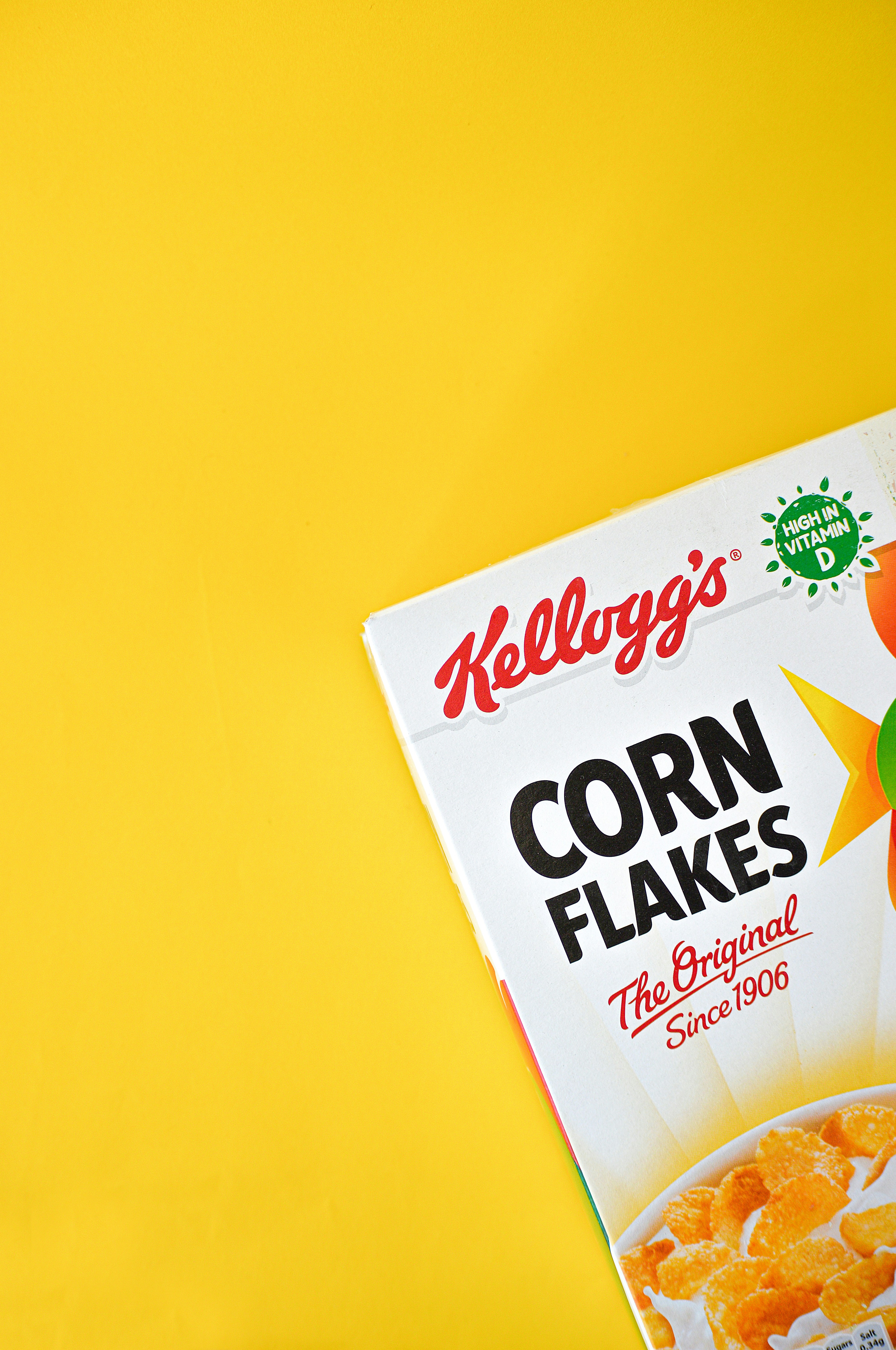 Kellogg's Corn Flakes emballage på en gul baggrund, med teksten "The Original Since 1906" og iconet "High in Vitamin D".