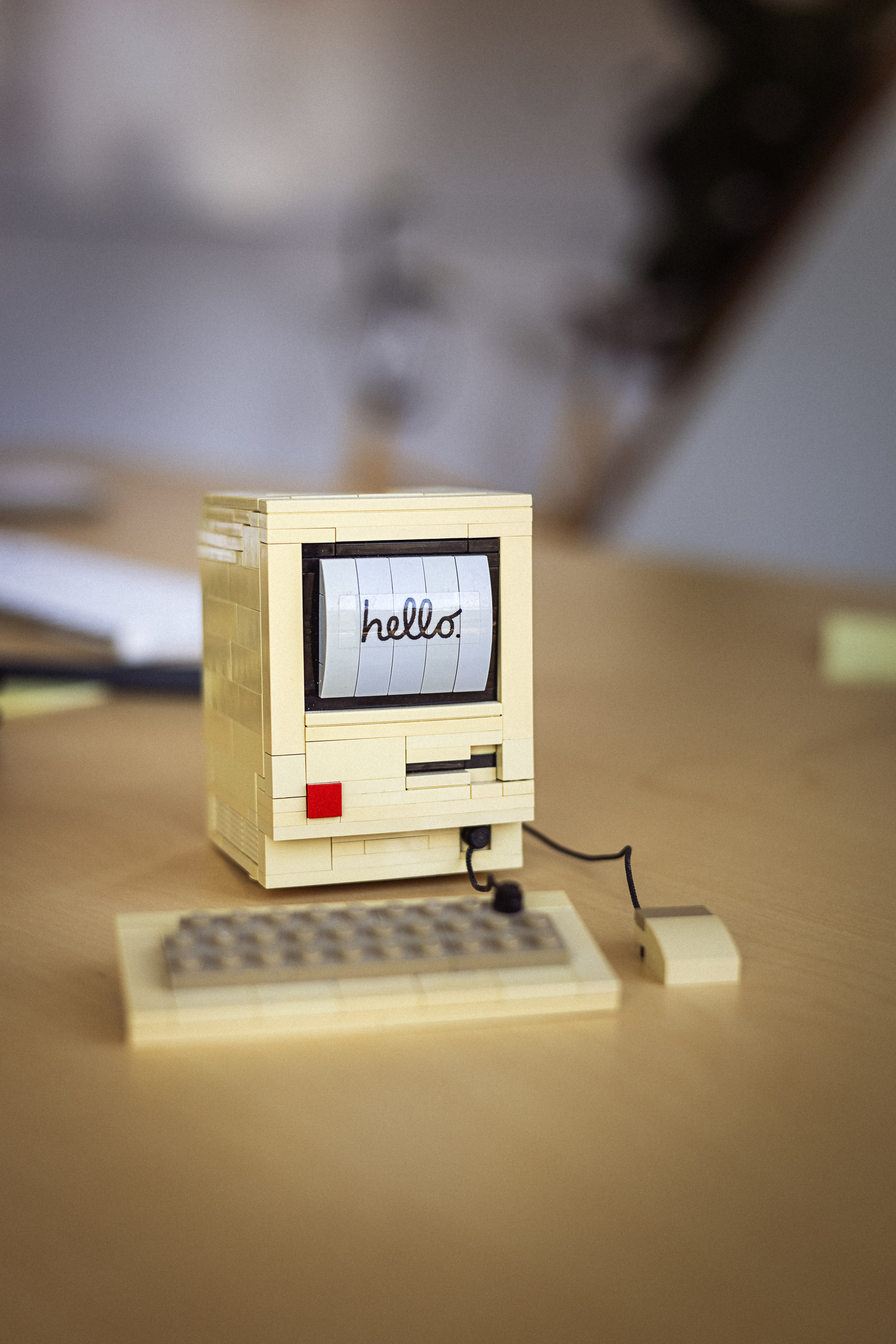LEGO-inspireret computer med teksten "hello" på skærmen, placeret på et skrivebord med en mus og tastatur ved siden af.