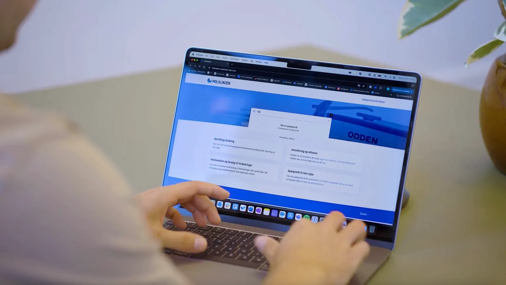 A person using a laptop to navigate a website interface with search functionality, featuring a blue theme and various sections, including options for booking, cancellations, and travel inquiries.