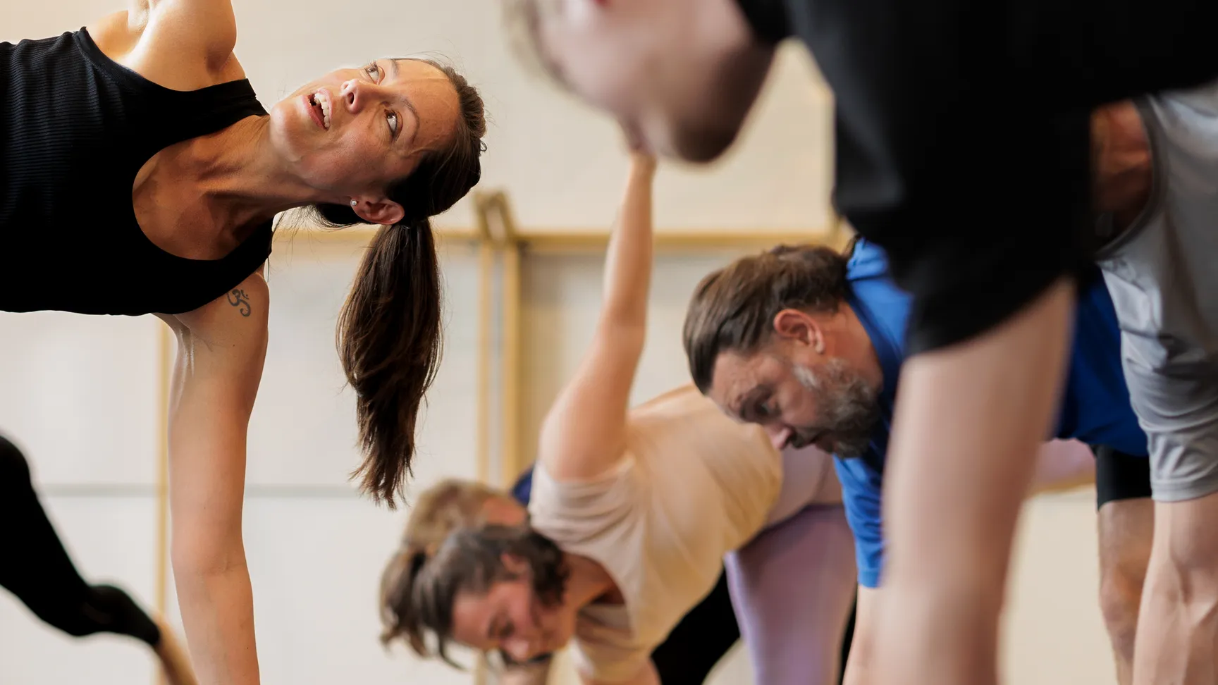 en gruppe persobner laver yoga og står i en yoga stilling