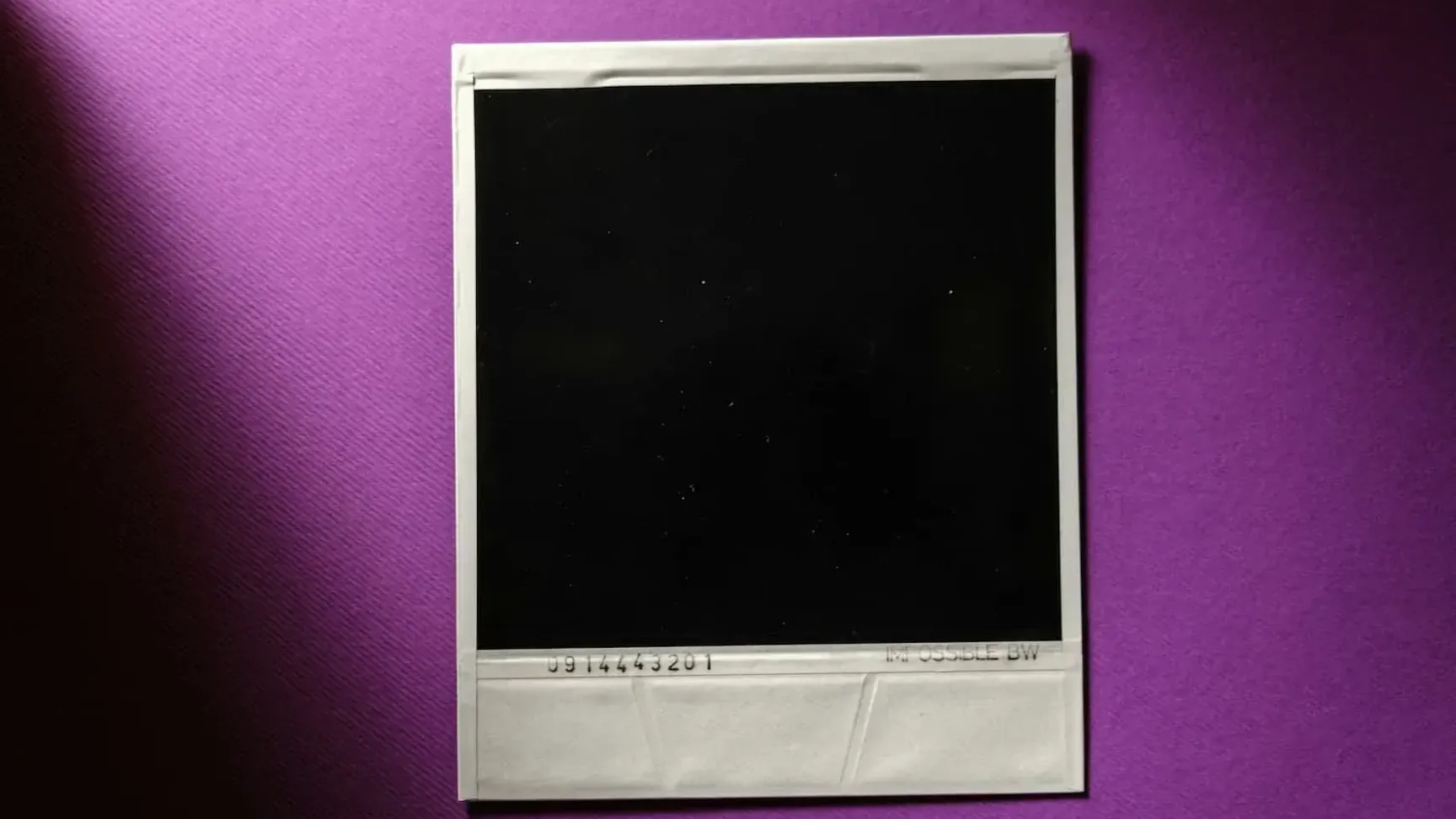 Sort polaroid-billede på lilla baggrund, viser en blank flade uden indhold.