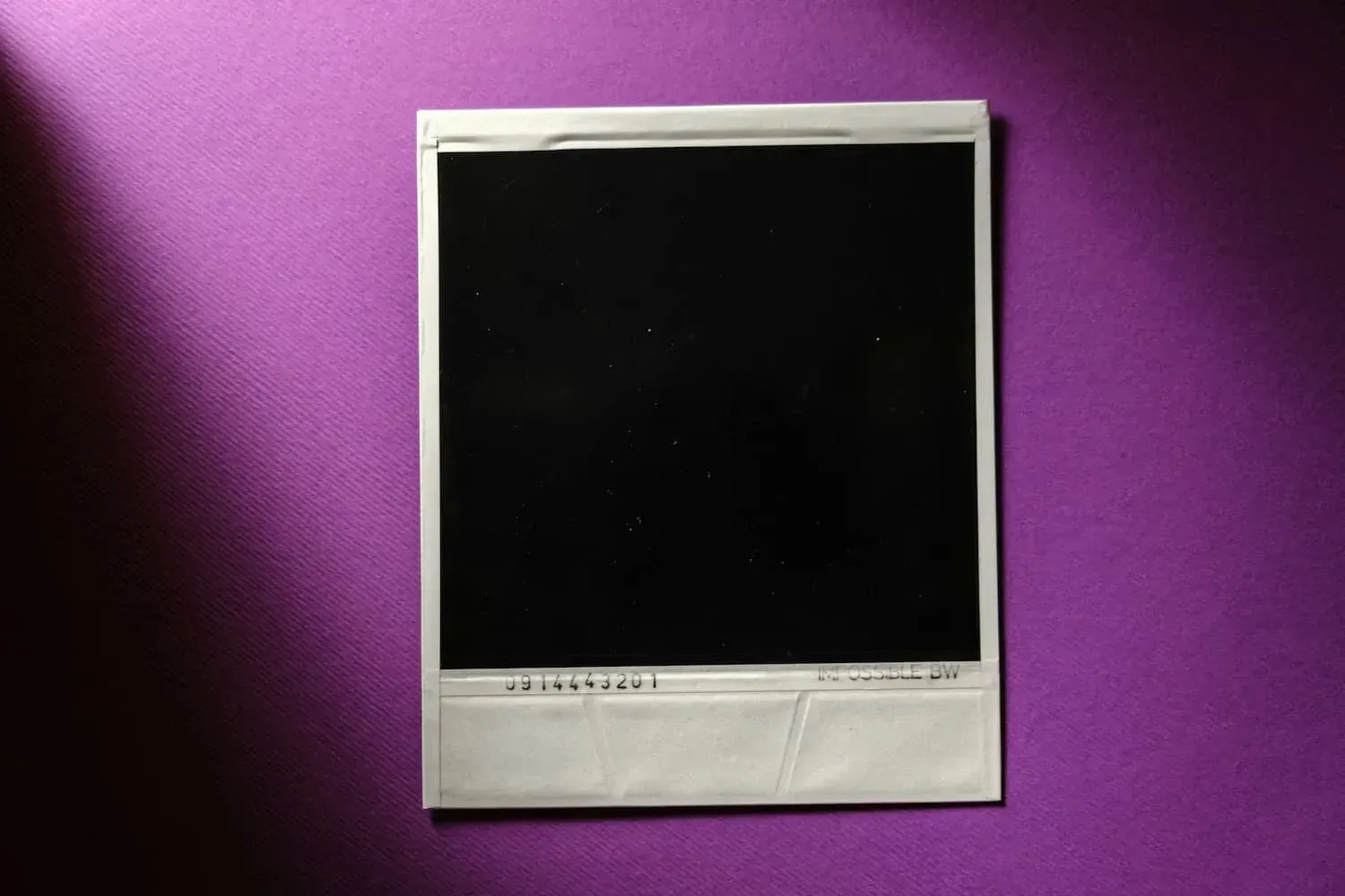 Sort polaroid-billede på lilla baggrund, viser en blank flade uden indhold.