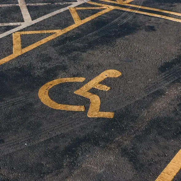 Gul handicap symbols på asfaltparkering, der indikerer plads til handicappede.