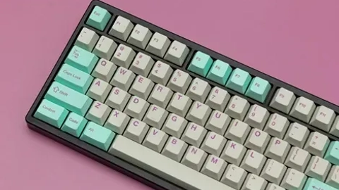 Et moderne mekanisk tastatur med farverige taster i mintgrøn og beige, placeret på en lyserød baggrund.