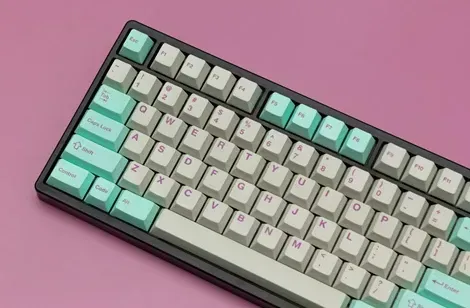 Et moderne mekanisk tastatur med farverige taster i mintgrøn og beige, placeret på en lyserød baggrund.