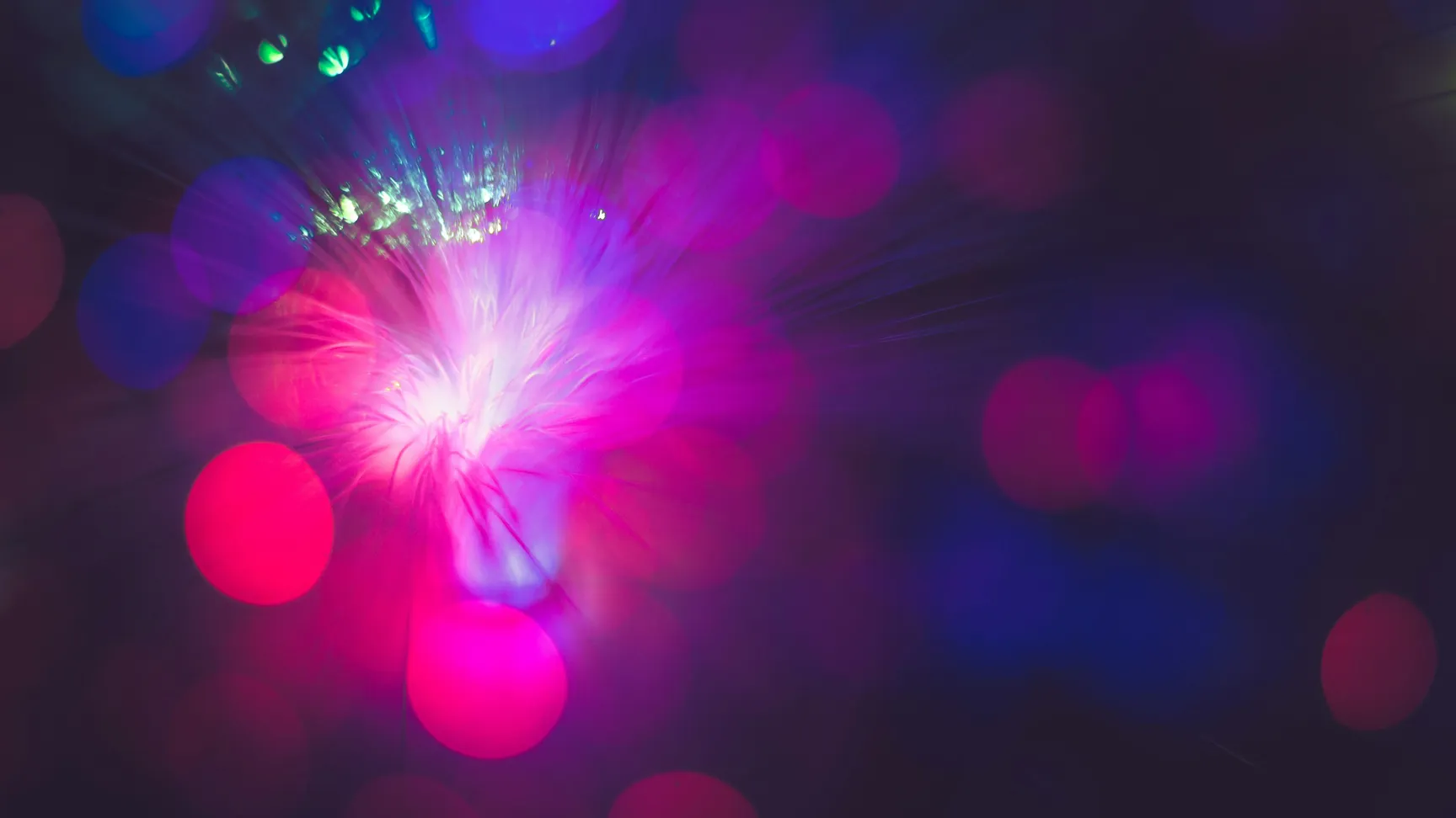 Et farverigt og abstrakt billede af lysglimt i nuancer af pink, lilla og blå, som skaber en dynamisk og drømmeagtig atmosfære med bløde bokeh-effekter.
