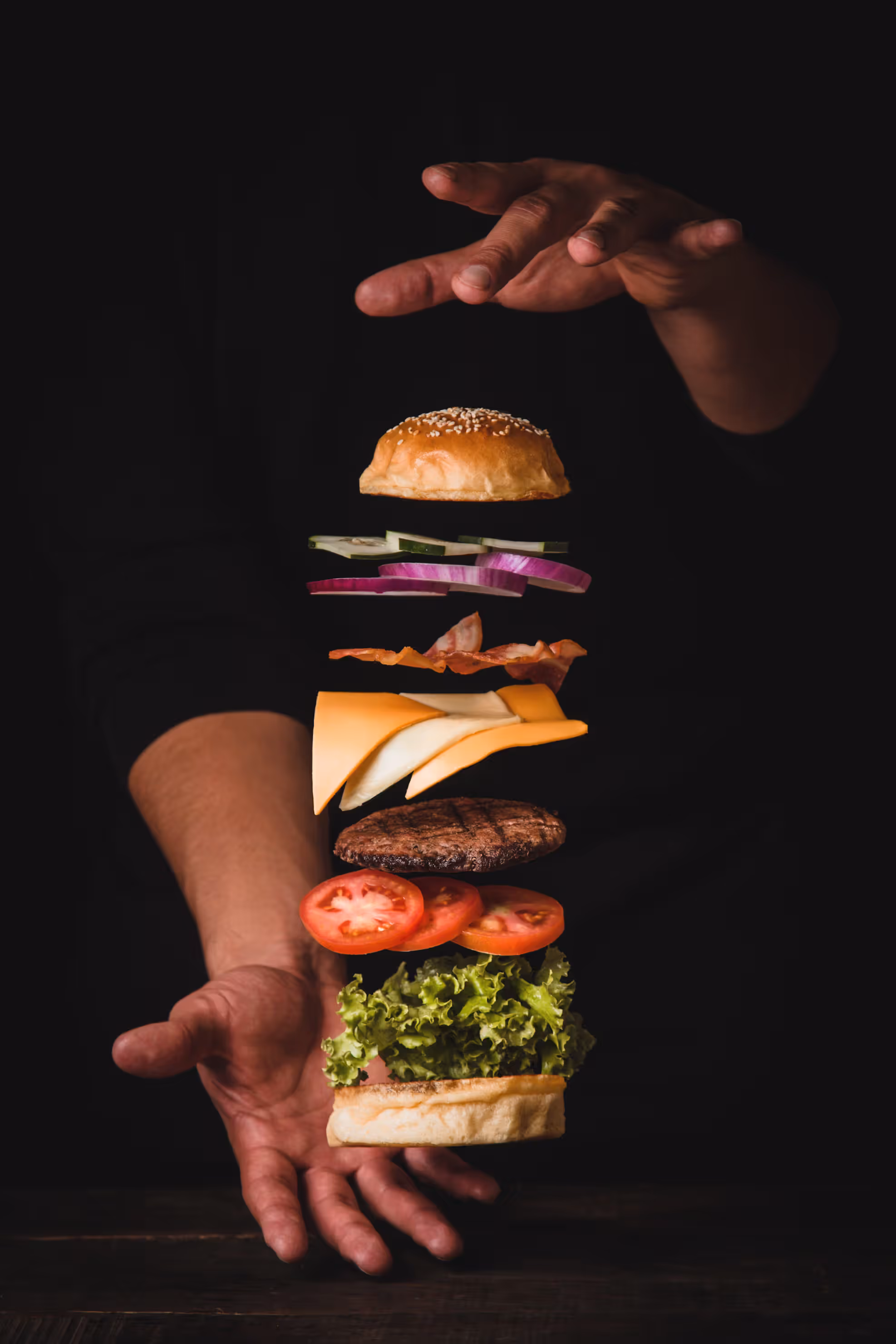 burger der flyver mellem mands hænder, den flyver så man kan se hver enkelt ting i burgeren