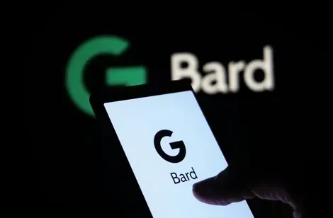 En hånd holder en smartphone med "G Bard" logoet på skærmen, i forgrunden er der et sløret baggrundsbillede af "G Bard" i grønt og hvidt.