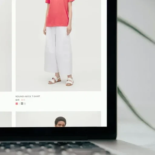 En model iført en lyserød rundhalset t-shirt og hvide brede bukser, præsenteret på en skærm med en online tøjbutik.
